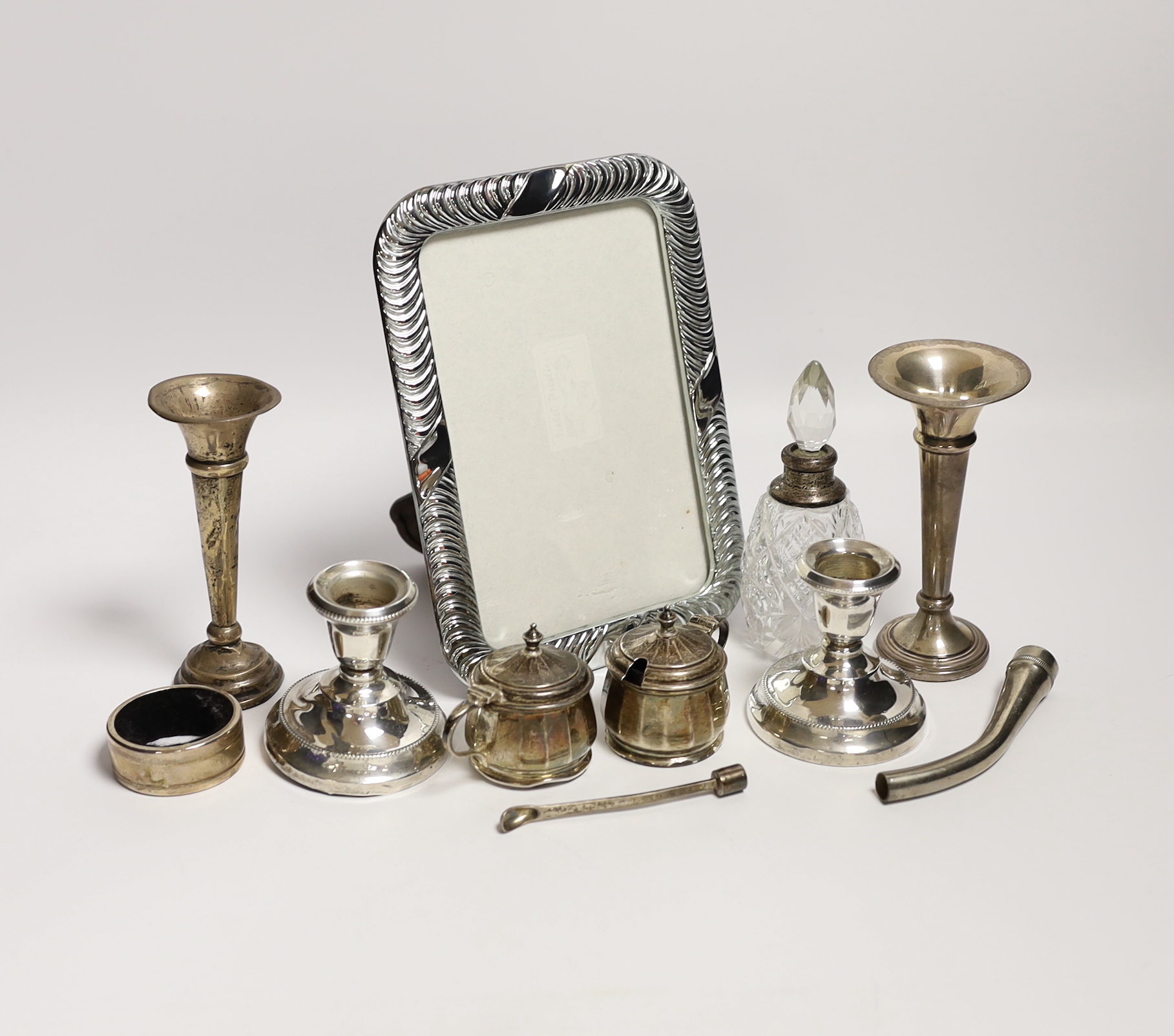 Sundry small silver including a pair of dwarf candlesticks, condiments, napkin ring, spill vases and a modern 925 mounted photograph frame.